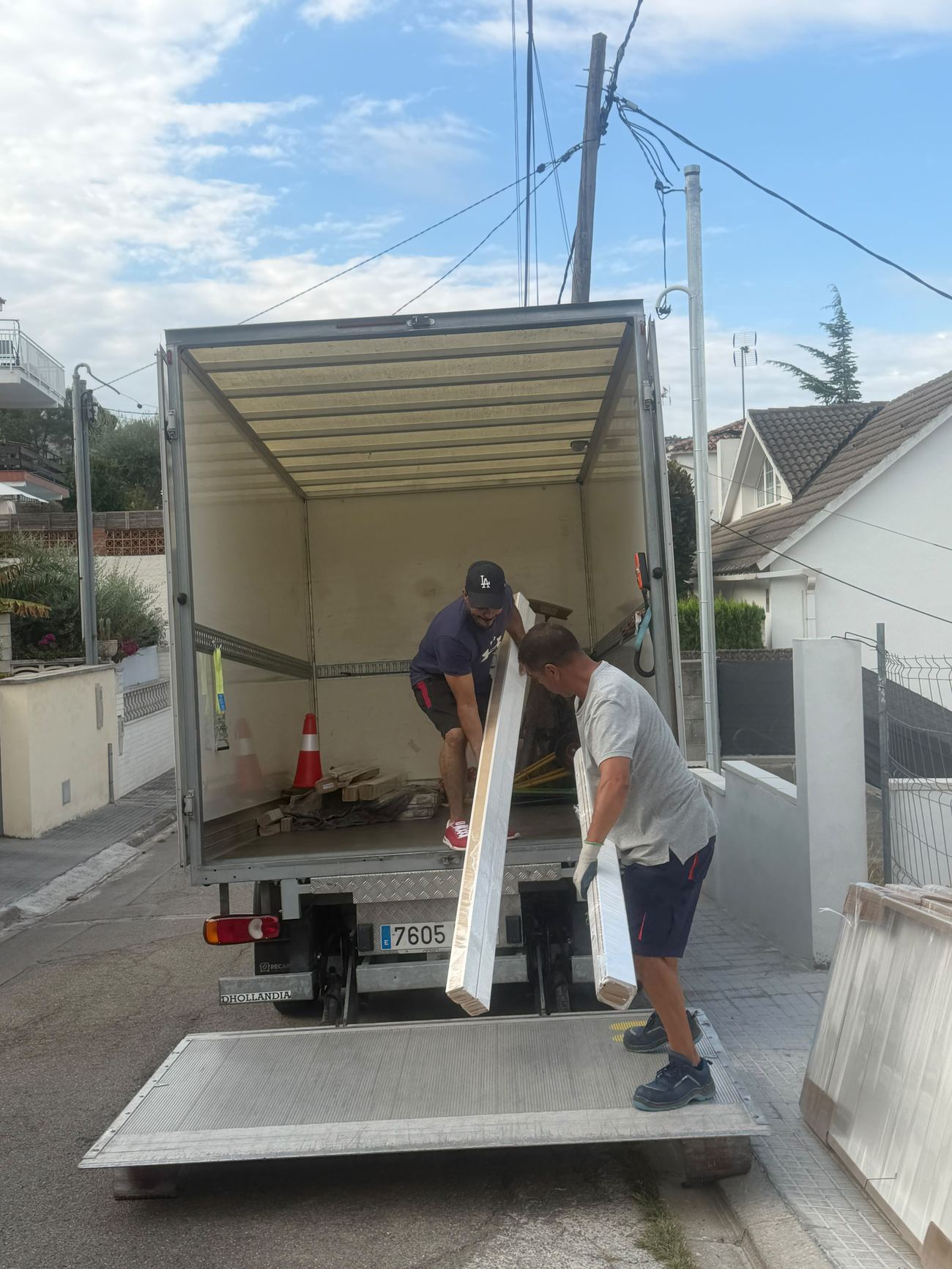 El equipo de Reina Transportes descargando vigas con la plataforma elevadora del camión