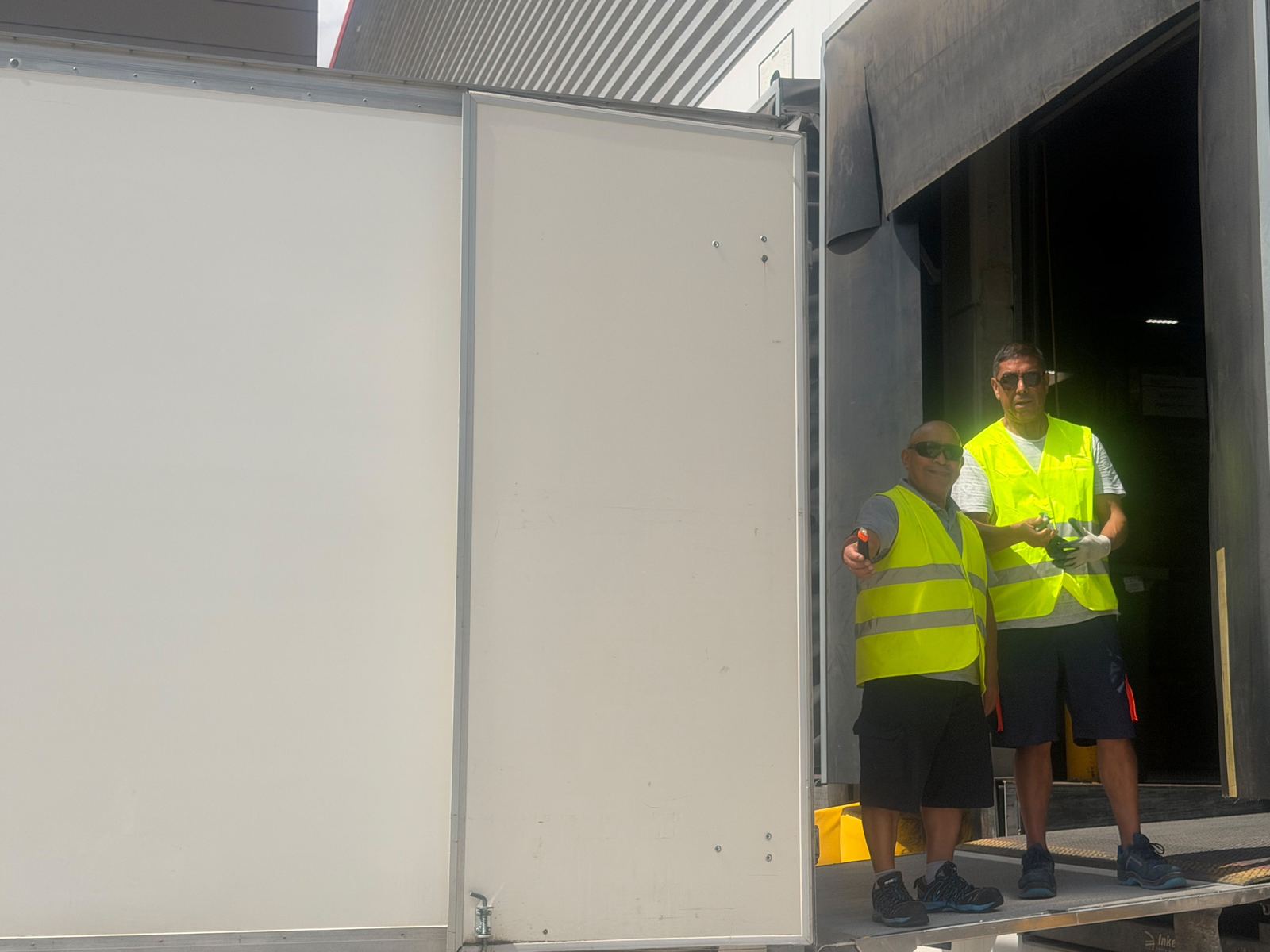 Dos personas del equipo de Reina Transportes con chaleco reflectante en un muelle de carga